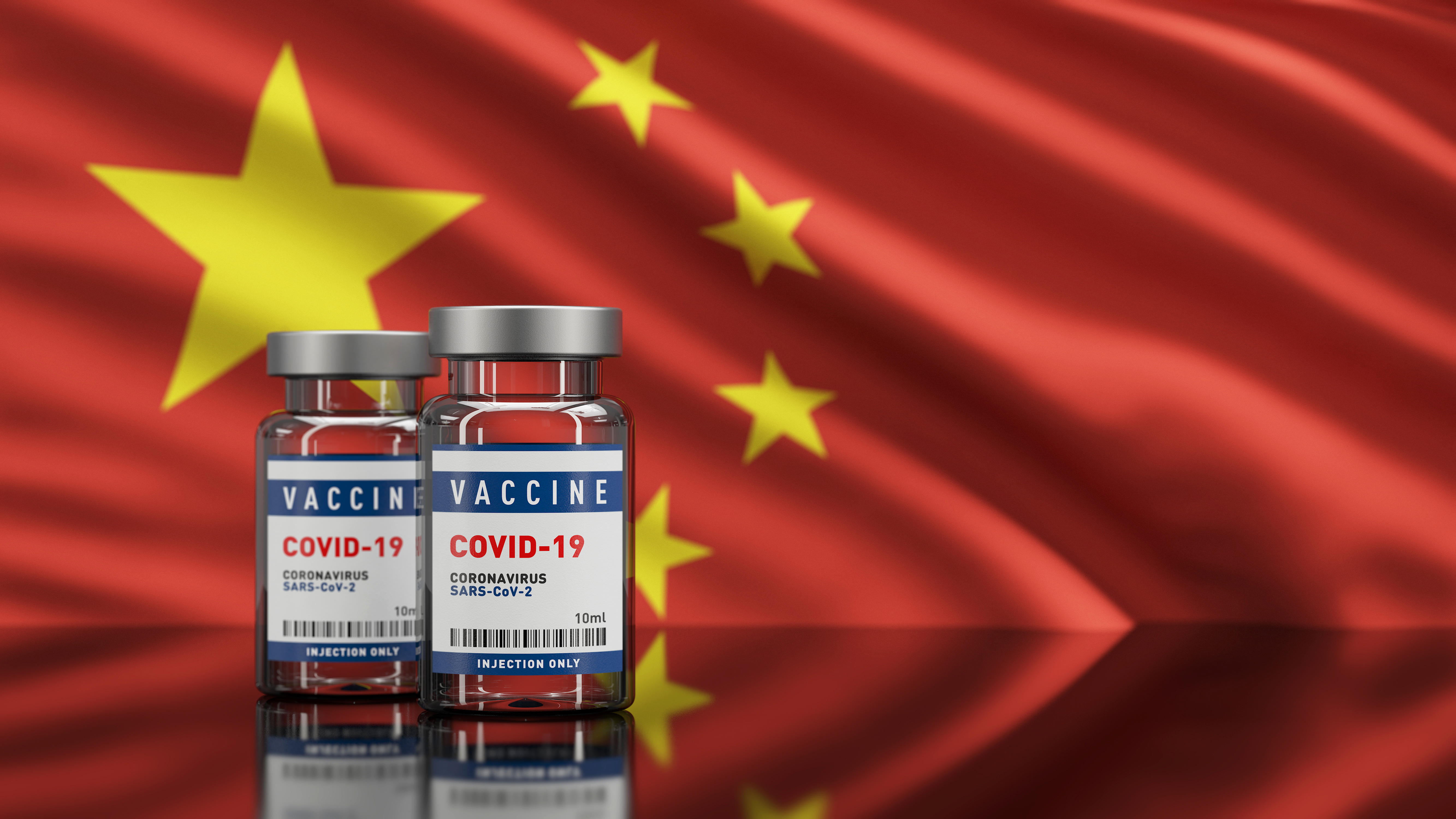 Photo showing two glass containers of COVID-19 vaccine with the Chinese flag in the background
